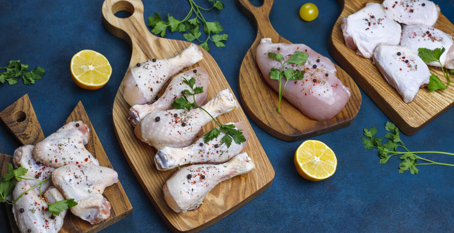 Raw chicken meat fillet, thigh, wings and legs with herbs ,spices,lemon and garlic on dark blue background. Top view